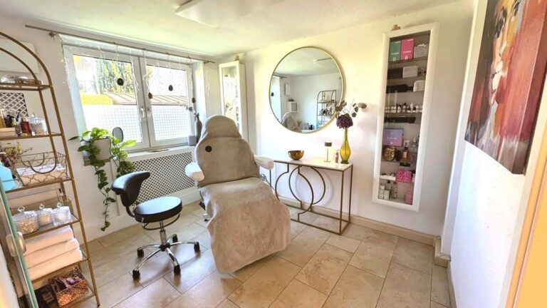 Freundlicher Behandlungsraum mit Behandlungsliege, Rundspiegel und Pigmenten für Permanent Make-up